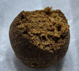 Round ball of hash broken open to show a soft, crumbly, resin-rich interior.
