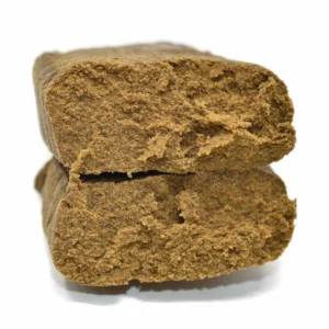 Close-up of two stacked pieces of golden, crumbly Moroccan hash showing a soft, dry texture.